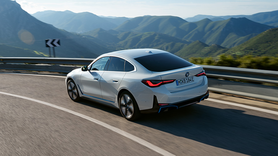 Three-quarter rear view BMW i4 eDrive40 G26 2021 driving BMW i4 eDrive40 G26 2021 Mineral White three-quarter rear view driving